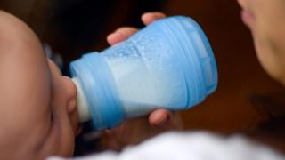 A French baby drinks milk from a bottle