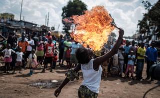 A member of Kenyan acrobat group Kibera Messenger breathes fire during a performance for filming in Kibera, Nairobi, on March 7, 2018.