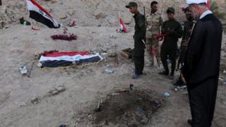 Iraqi Shia fighters examine a burial site thought to hold victims of the Camp Speicher massacre.