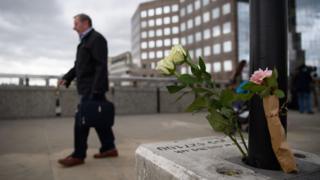 Man walks past floral tribute on London Bridge following the June 2017 attack