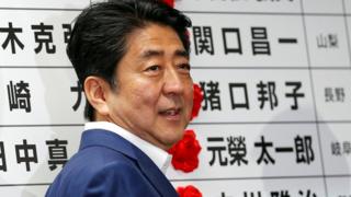 自民党開票センターで、当選確実となった候補に花をつける安倍氏(10日)