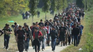 Migrants walk from Hegyeshalom on the Hungarian border walk into Austria on 23 September 2015