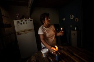 An older woman lights a candle