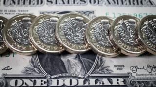 Row of new pound coins on one dollar bill