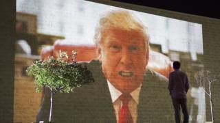 A videowall shows a speech by Donald Trump