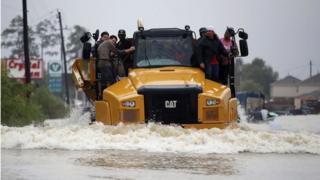 Varias personas huyen de las inundaciones aferrados a un camión en Houston.