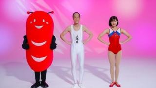 Hideo Higashikokubaru stars with a gymnast (R) and an alien sausage mascot (L)