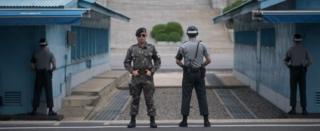 South Korean soldiers stand guard before North Korea's Panmon Hall (rear C) and the military demarcation line separating North and South Korea, at Panmunjom, on 6 August