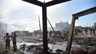 Citizens stand amid the burnt-out wreckage of the Iron Market.