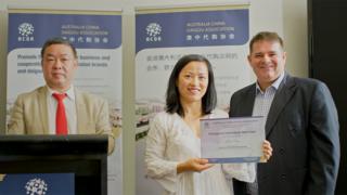 An Australia-based daigou receives her membership certificate from the Australia China Daigou Association