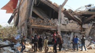 People gather around the rubble of a hospital supported by Doctors Without Borders (MSF) near Maaret al-Numan, in Syria's northern province of Idlib, on 15 Febrary 2016.