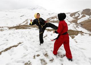 Sima Azimi, a trainer at the Shaolin Wushu club, and Shakila Muradi, show their Wushu skills to other students on a hilltop in Kabul, Afghanistan.