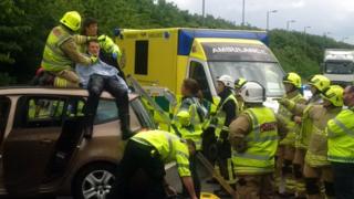 The motorcyclist on the roof of the car after the crash on the A41