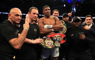 Anthony Joshua en un ring rodeado de entrenadores y con el cinturón de campeón.