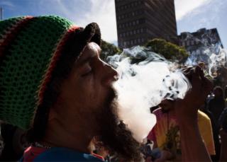 A man smokes marijuana out of a bottle-neck pipe, joining about 1500 people as they protest in front of the South African Parliament, to call for the complete legalisation of Cannabis or Marijuana in South Africa, on May 5, 2018, in Cape Town