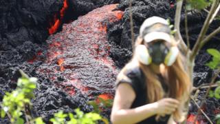 Lava flows at a new fissure in the aftermath of eruptions from the Kilauea volcano on Hawaii's Big Island as a local resident walks nearby after taking photos on 12 May 2018 in Pahoa, Hawaii
