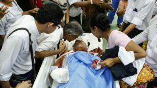 Injured Naing Ngan Lin lies on a bed as his father (L) and spouse (R) talks to him at Yangon General Hospital, Yangon, Myanmar (29 October 2015)