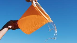 A bucket with water in it being tipped