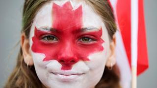Una joven con la cara pintada con los colores de la bandera de Canadá.