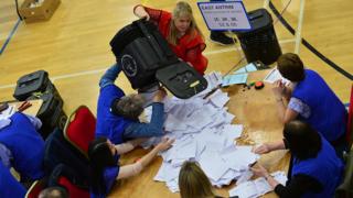 Election count staff empty a ballot box