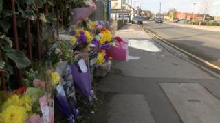 Flowers left at railings on a road