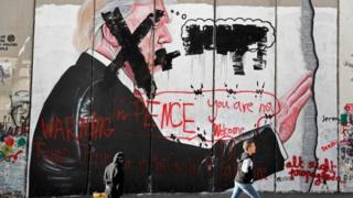 Palestinian children walk past vandalised graffiti depicting US President Donald Trump and slogans saying US Vice-President Mike Pence is "not welcome" in Bethlehem, West Bank, 7 December 2017
