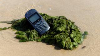 teléfono móvil descatalogado en la orilla de la playa.