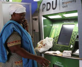 Rebecca Palai speaks on the phone with a consultant as she withdraws her medication at an ATM pharmacy which allows patients with chronic illnesses to receive repeat medication within three minutes, in Alexander township, South Africa, March 15, 2018.