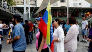 woman with flag waits to vote in Caracas