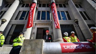 Greenpeace activists scaled two entrance pillars to drop banners at the Canadian High Commission
