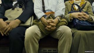 Homem sentado entre dois outros no trem