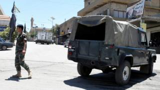A Lebanese army soldier walks near a military vehicle at the entrance of the border town of Arsal, in eastern Bekaa Valley, Lebanon June 30, 2017