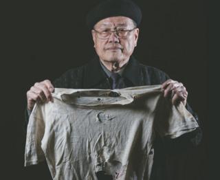 潘信行依舊保存著父親受刑時所穿、被彈孔穿過的衣服。