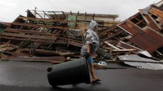 Una mujer camina frente a una construcción derrumbada por María en Fajardo.