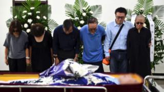 Liu Xia crying with other mourners beside her husband's coffin