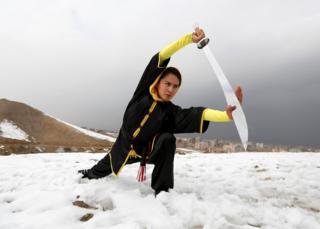 Sima Azimi, 20, a trainer at the Shaolin Wushu club, shows her Wushu skills to other students on a hilltop in Kabul, Afghanistan.
