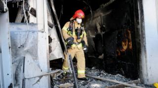 A firefighter walks out of a burnt hospital in Miryang, South Korea