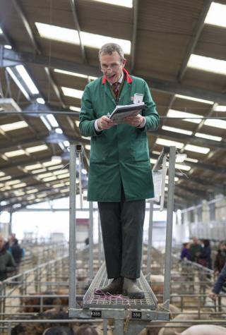 A auctioneer stands with his clipboard