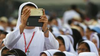 A nun takes a photo with an iPhone