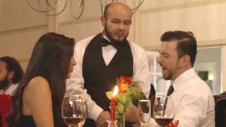 Escena de aviso en el que una pareja en un restaurante habla con el mozo.