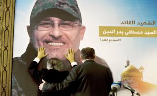 Adnan Badreddine, left, brother of top Hezbollah commander Mustafa Badreddine, grieves at his brother's picture in a southern suburb of Beirut, Lebanon, Friday, May 13, 2016.
