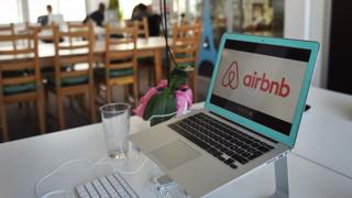 The AirBnB logo is displayed on a computer screen at the AirBnB offices in Paris.