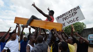 Protestors carry coffins as they wave placards during a rally in front of the morgue of Yopougon University Hospital in Abidjan on March 7, 2018, as they stage a protest against IVOSEP - the dominant funeral service provider in Ivory Coast. Hundreds of small undertaker firms in Ivory Coast have gone on strike over what they described as abusive practices by the country's dominant funeral company.