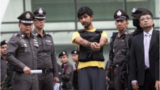 Police officers escort a key suspect in last month's Bangkok bombing, yellow shirt, identified by Thai police as Yusufu Mieraili