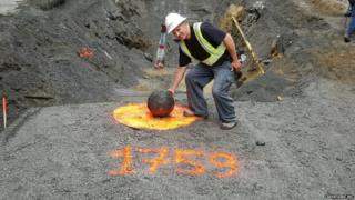 A worker poses beside the cannonball in Quebec