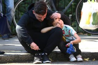 Un hombre sostiene la cabeza a un niño fuera de la Torre Grenfell, el edificio de viviendas incendiado en Londres.