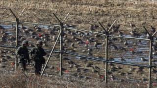 South Korean soldiers patrol a fence near the DMZ