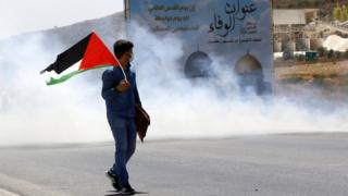 متظاهر يلوح بالعلم الفلسطيني خلال اشتباكات مع القوات الإسرائيلية قرب نابلس