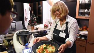 Vorwerk Thermomix representative Brigitte Heyde (R) presents Vorwerk's latest Thermomix cooking machine TM5 to a group of potential buyers at a private kitchen in Berlin on Dezember 1, 2014.