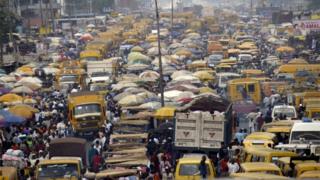 People walk struggling for space between public transport buses and trucks at the bustling Oshodi bus stop in Lagos 06 February 2006.